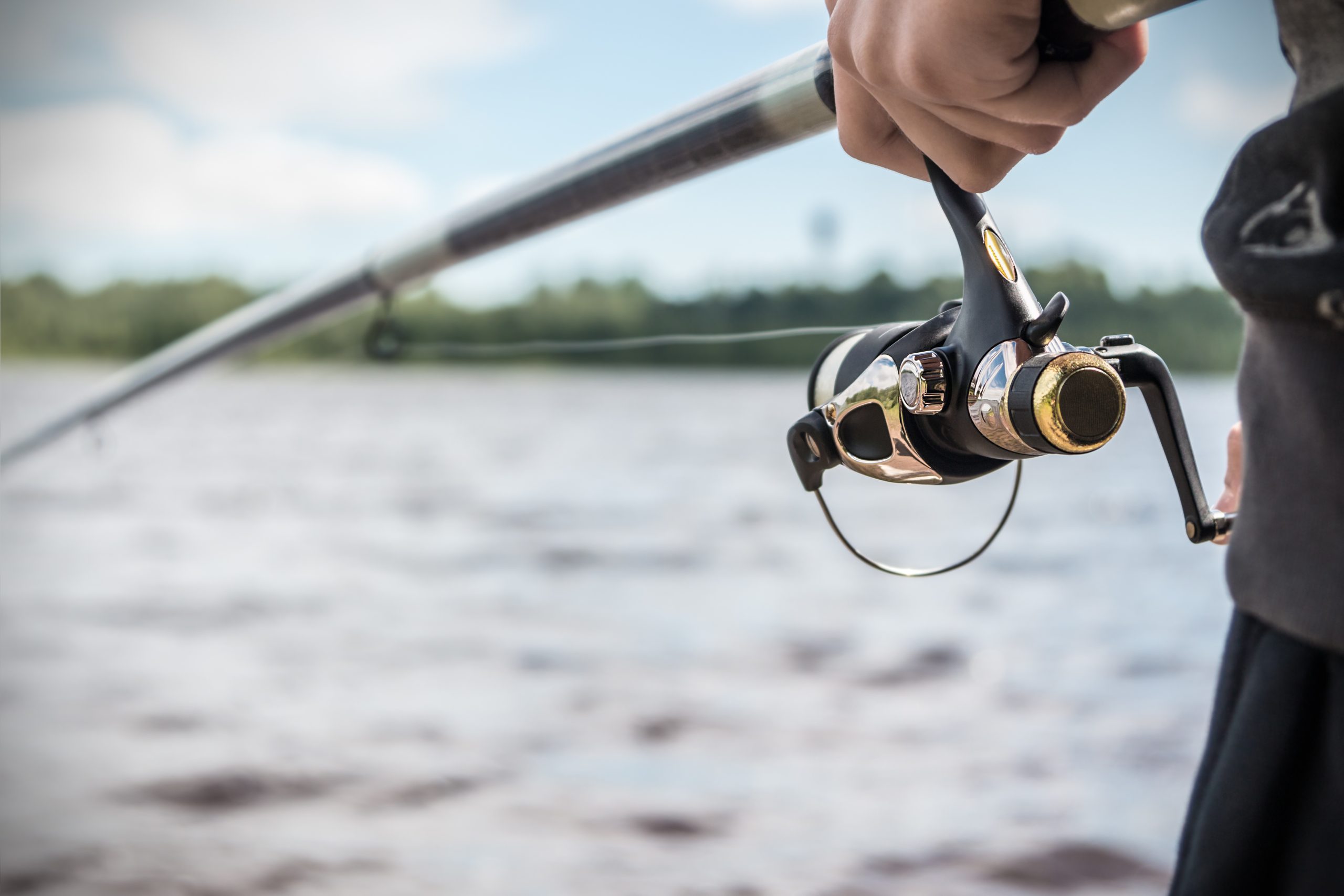 hand holding a fishing rod with reel