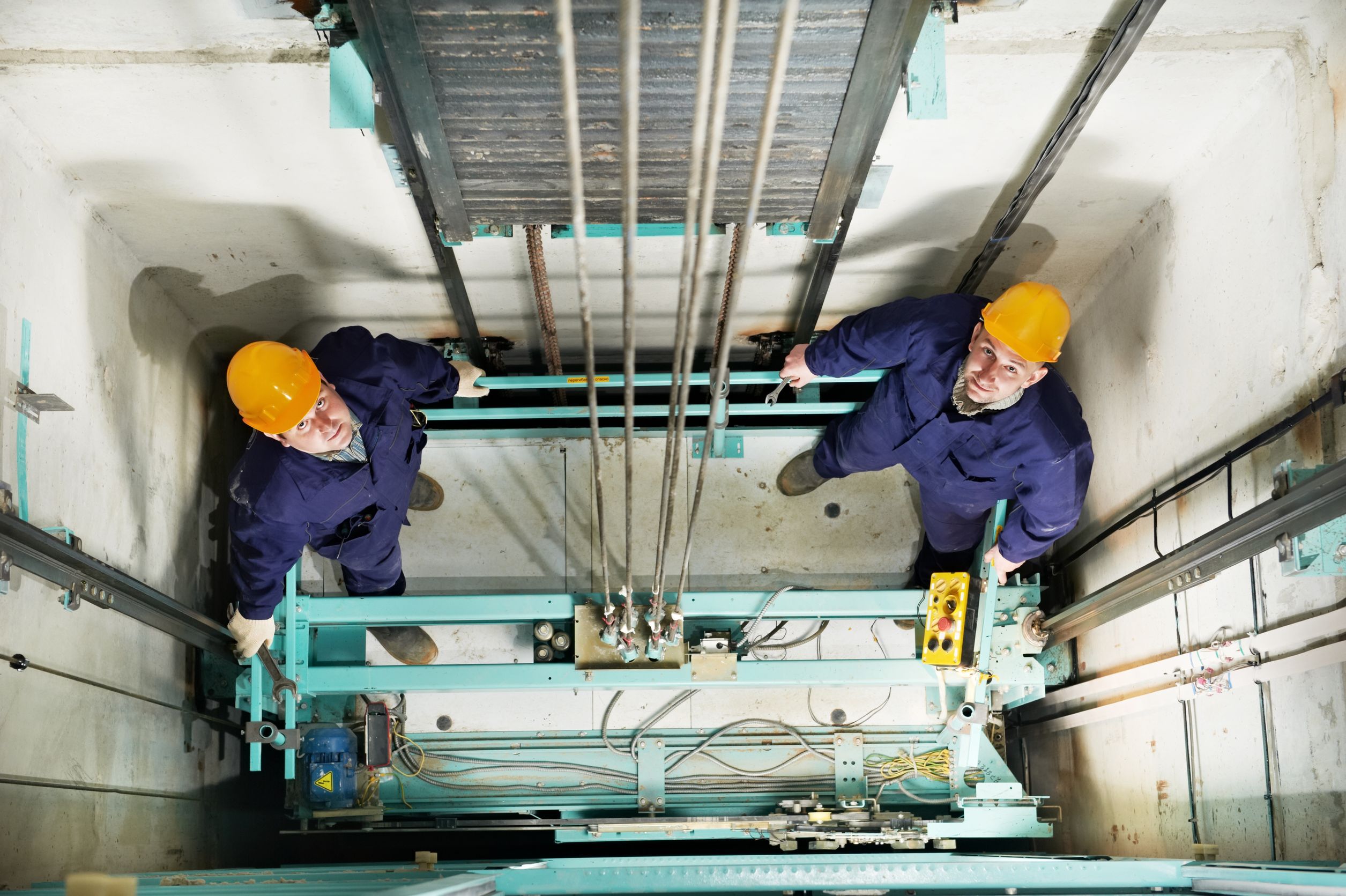 16404884_l-machinists-adjusting-lift-in-elevator-hoist-way-